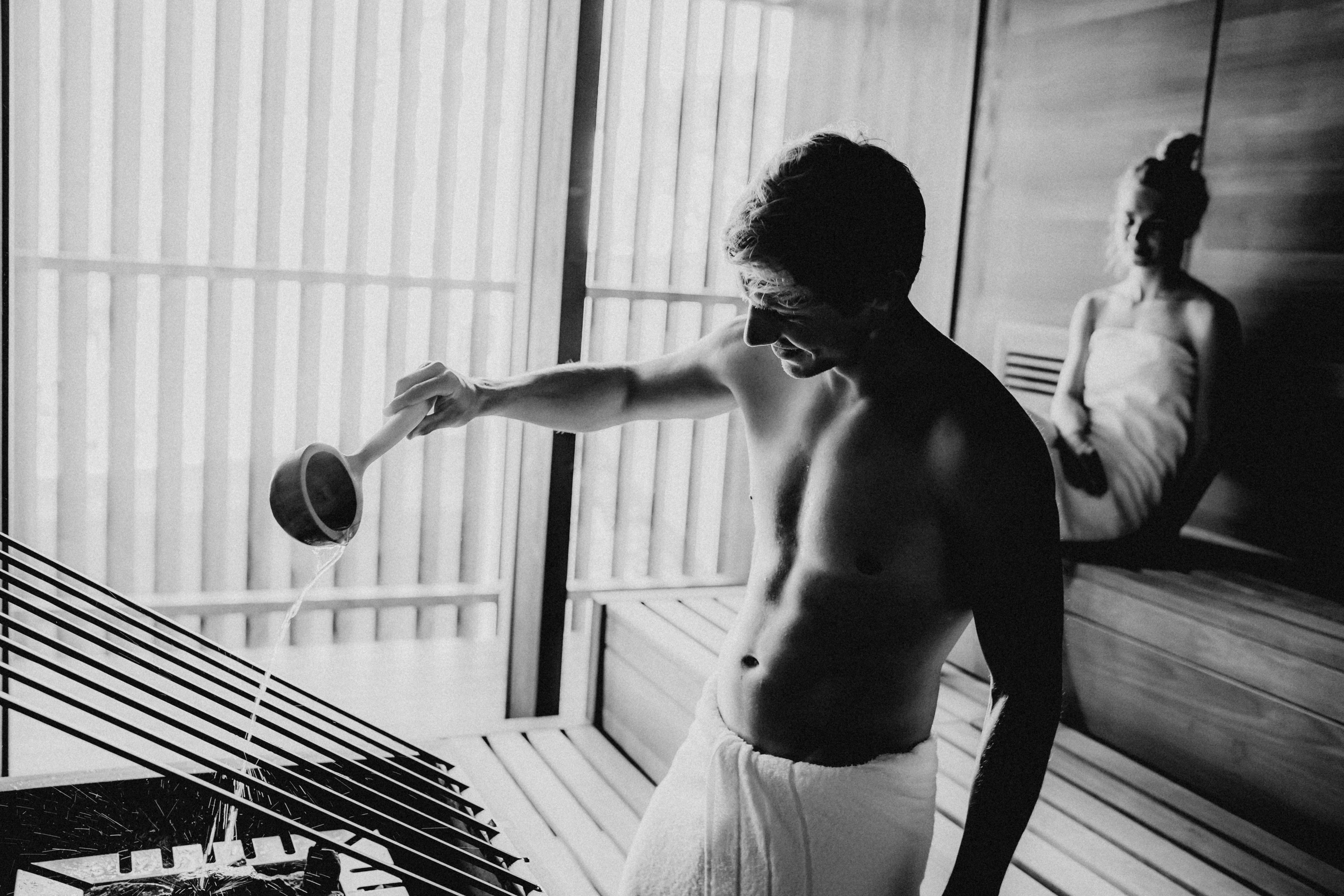 A cozy hotel room featuring a bed, lamp, and curtains in black and white tones.