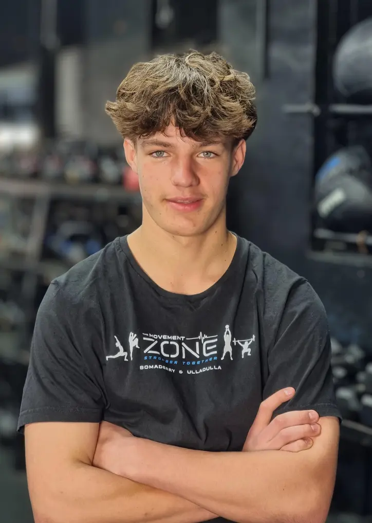 Coach Anto Newton posing in The Movement Zone shirt inside the training facility.