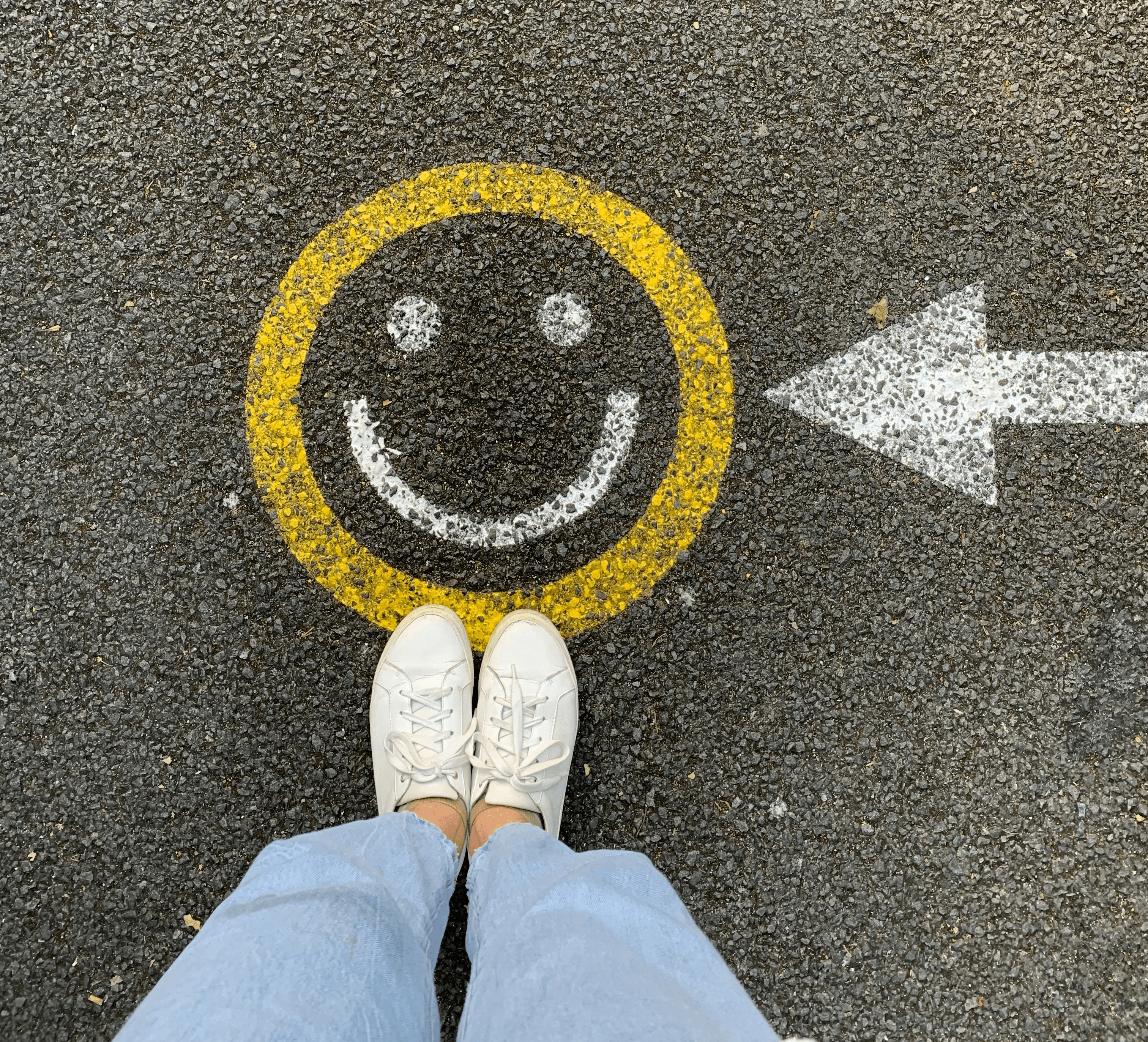 person in white shoes standing on gray concrete road