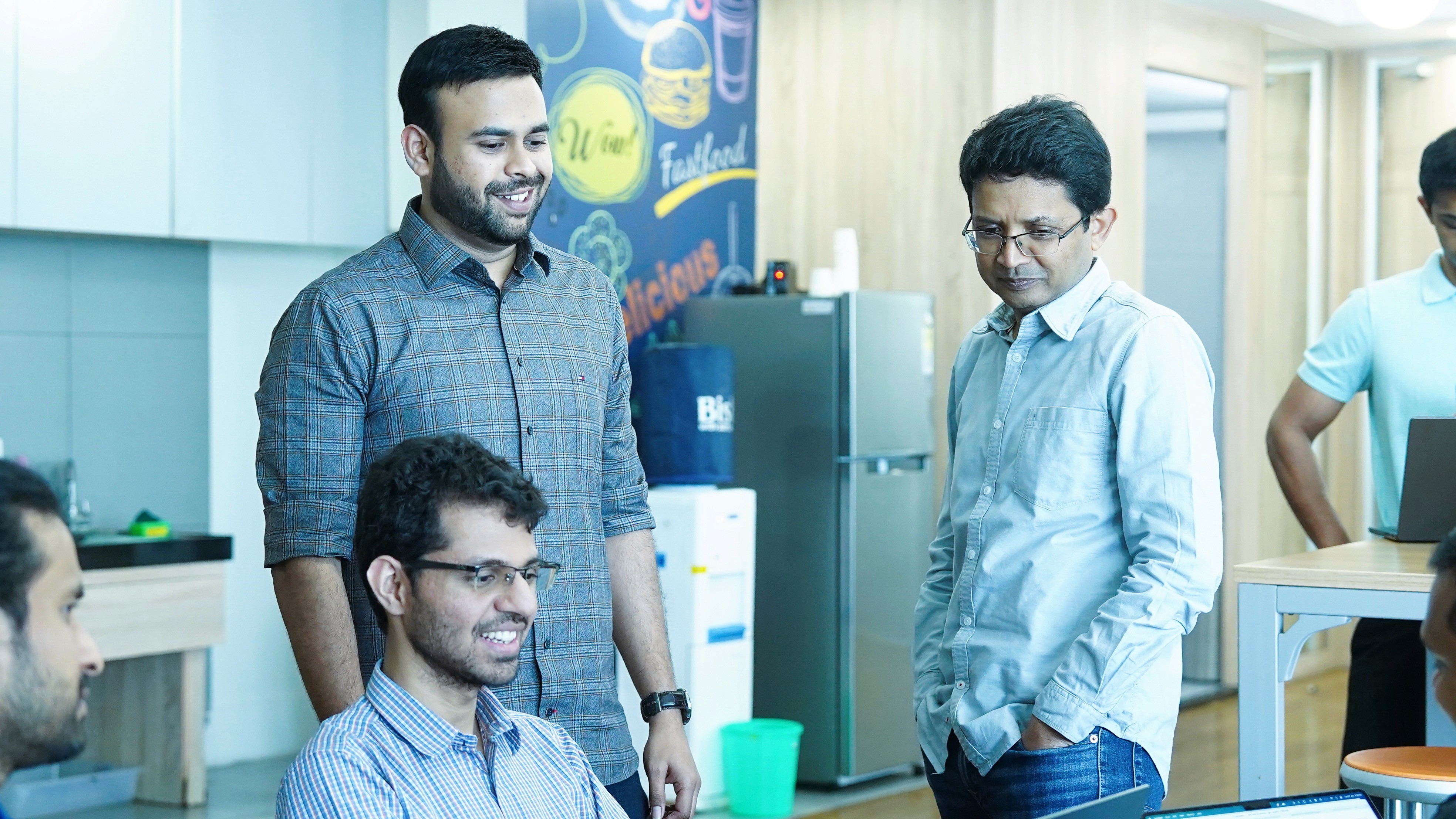 three men laughing while looking in the laptop inside room