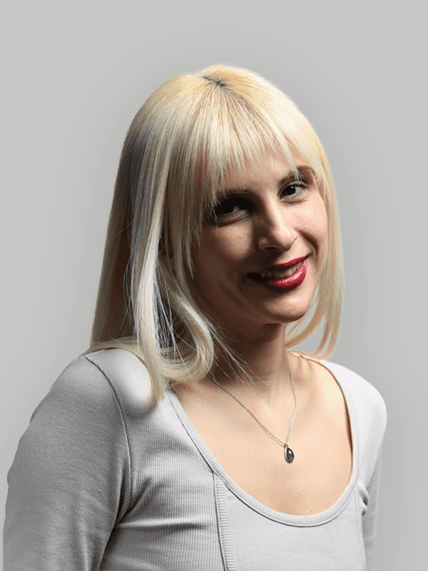 A woman with straight blonde hair wearing a light colored sweater looks away.