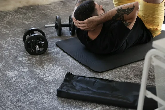 Man resting on an exercise mat beside dumbbells