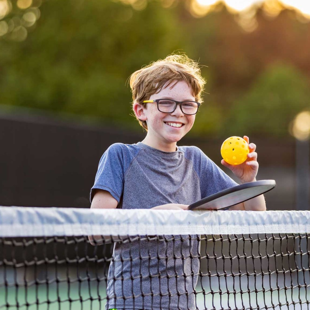 Enfant avec un grand sourir en pleine partie de pickleball au domaine de la brame