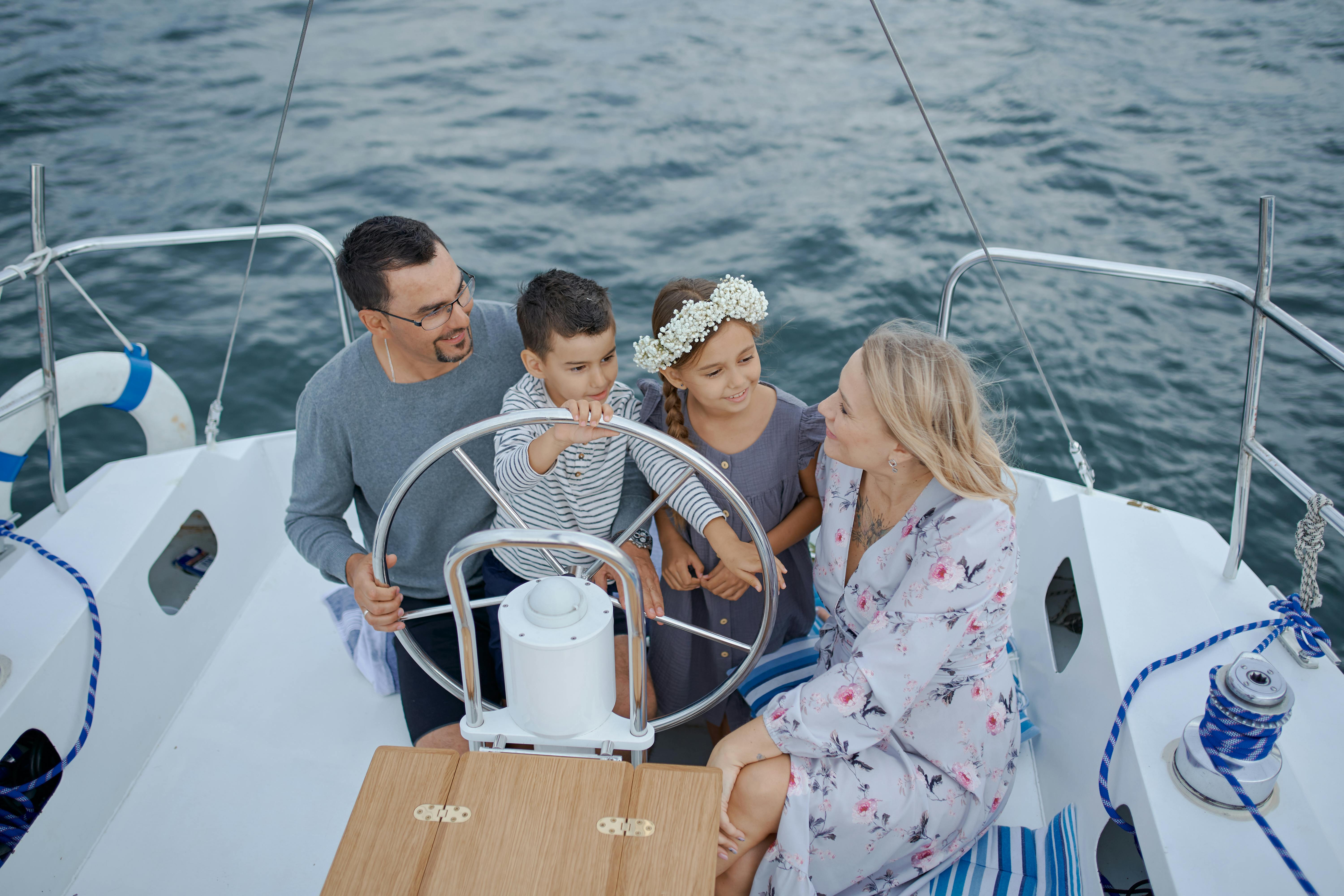 A family enjoys a peaceful sailing trip, sitting on a white yacht deck with a steering wheel, surrounded by calm blue water.