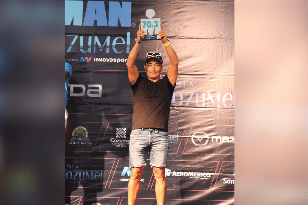 Atleta en el podio sosteniendo un trofeo en alto tras la premiación.