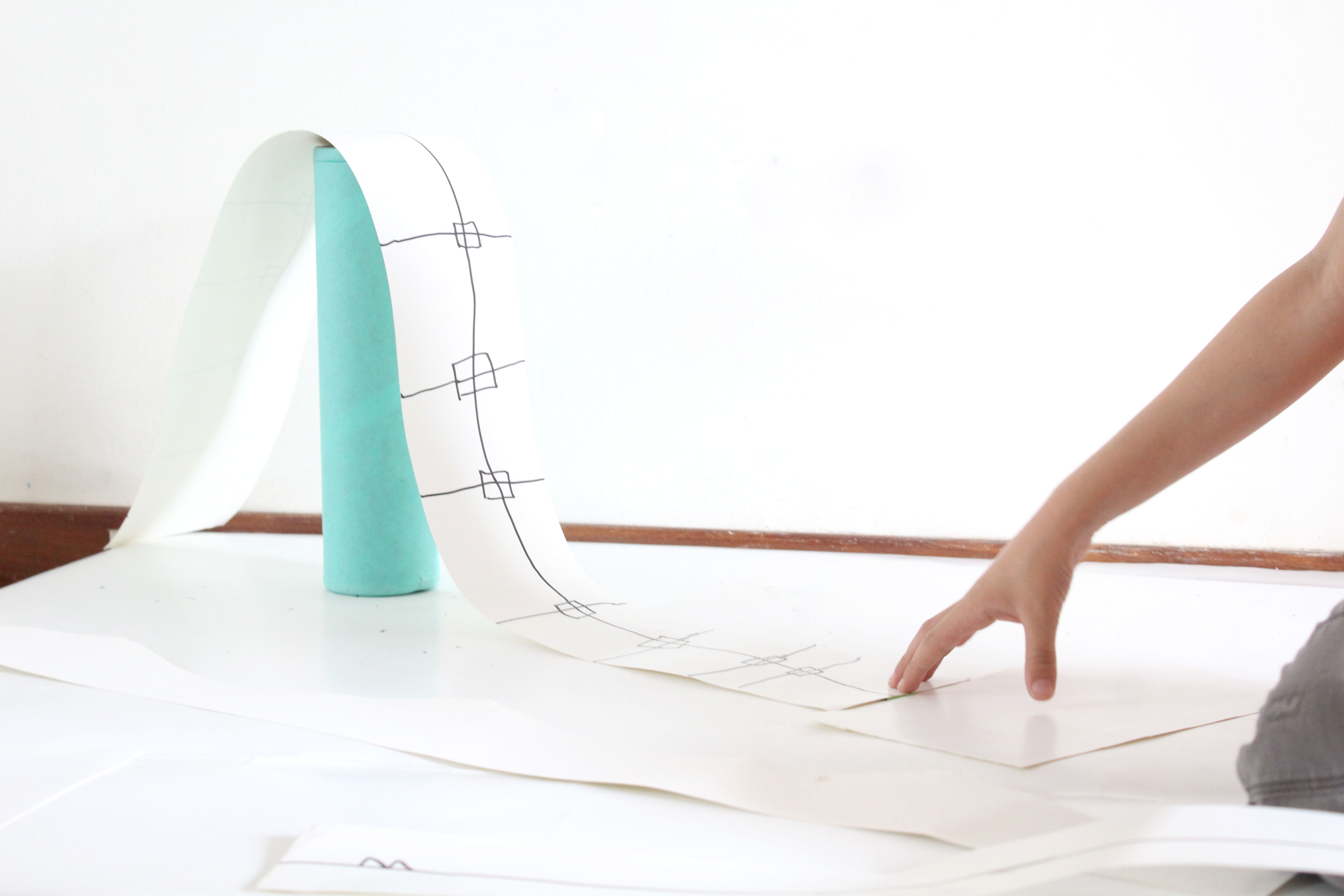 Niños explorando diseño espacial con un rollo de papel curvado y marcas en una actividad creativa