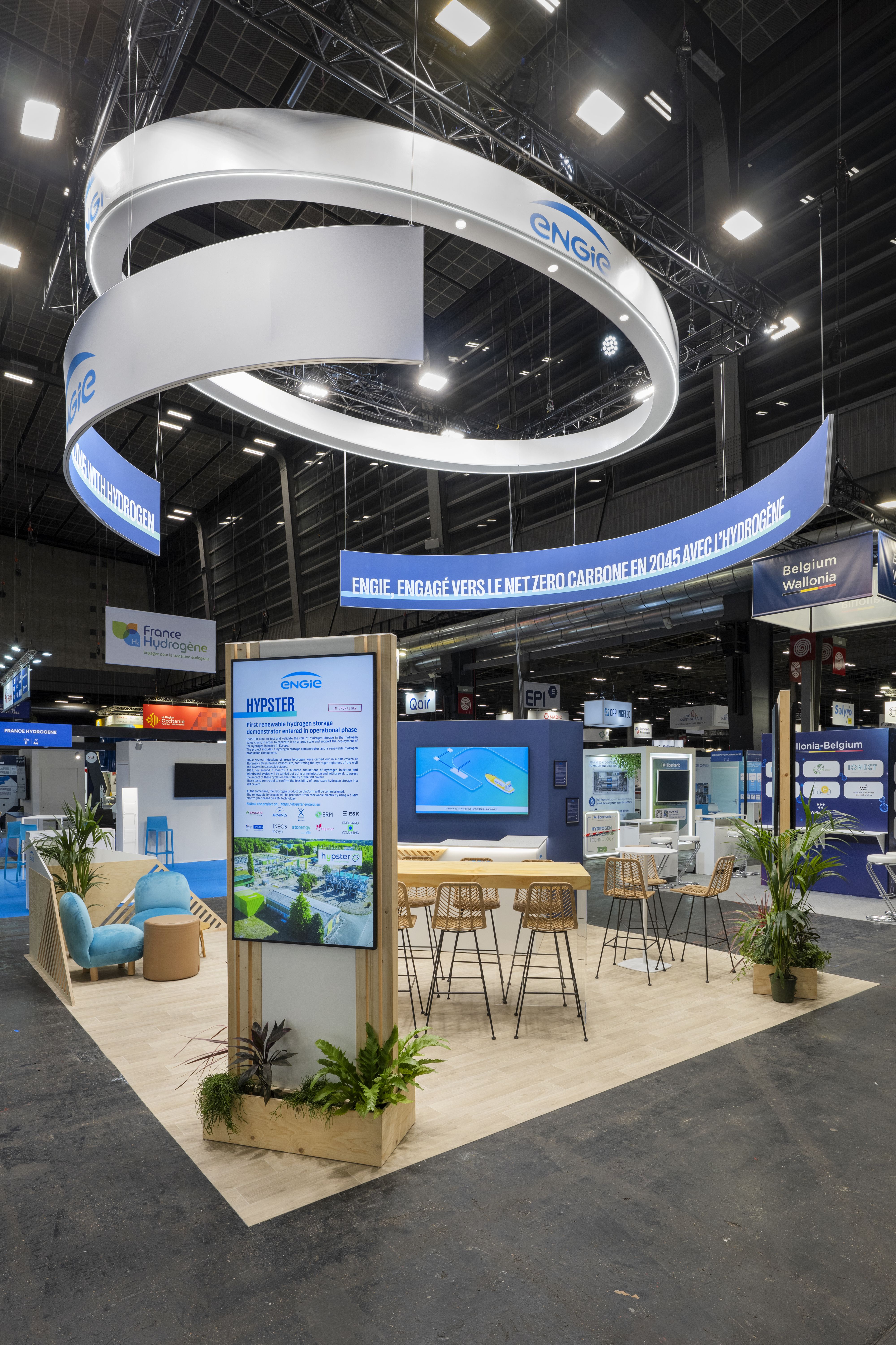 Stand ENGIE Hyvolution Paris 2026 par Expace – vue d'ensemble avec anneau lumineux architectural suspendu, mobilier organique bois et espace d'échange énergie hydrogène bas carbone