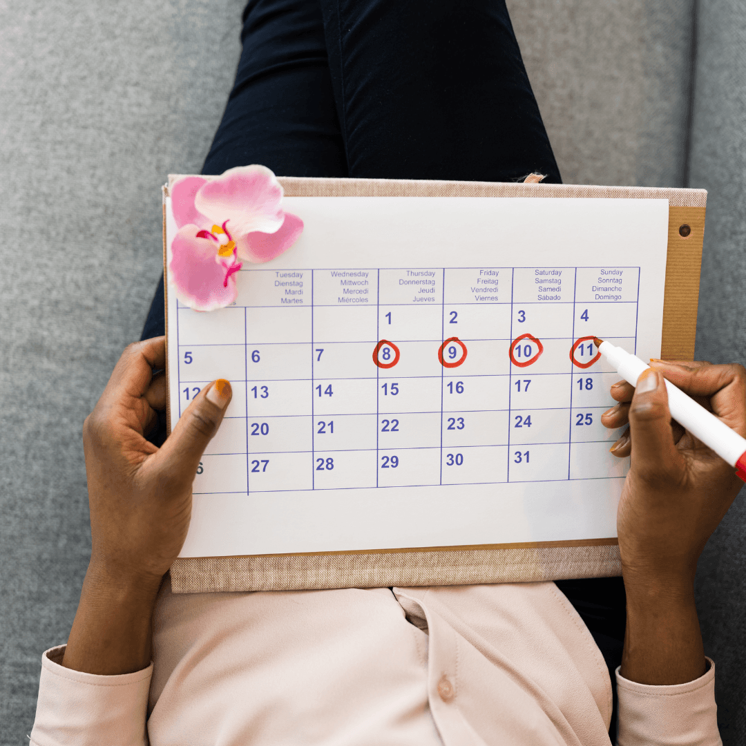Hands marking dates on calendar, representing fertility cycle tracking and treatment planning.