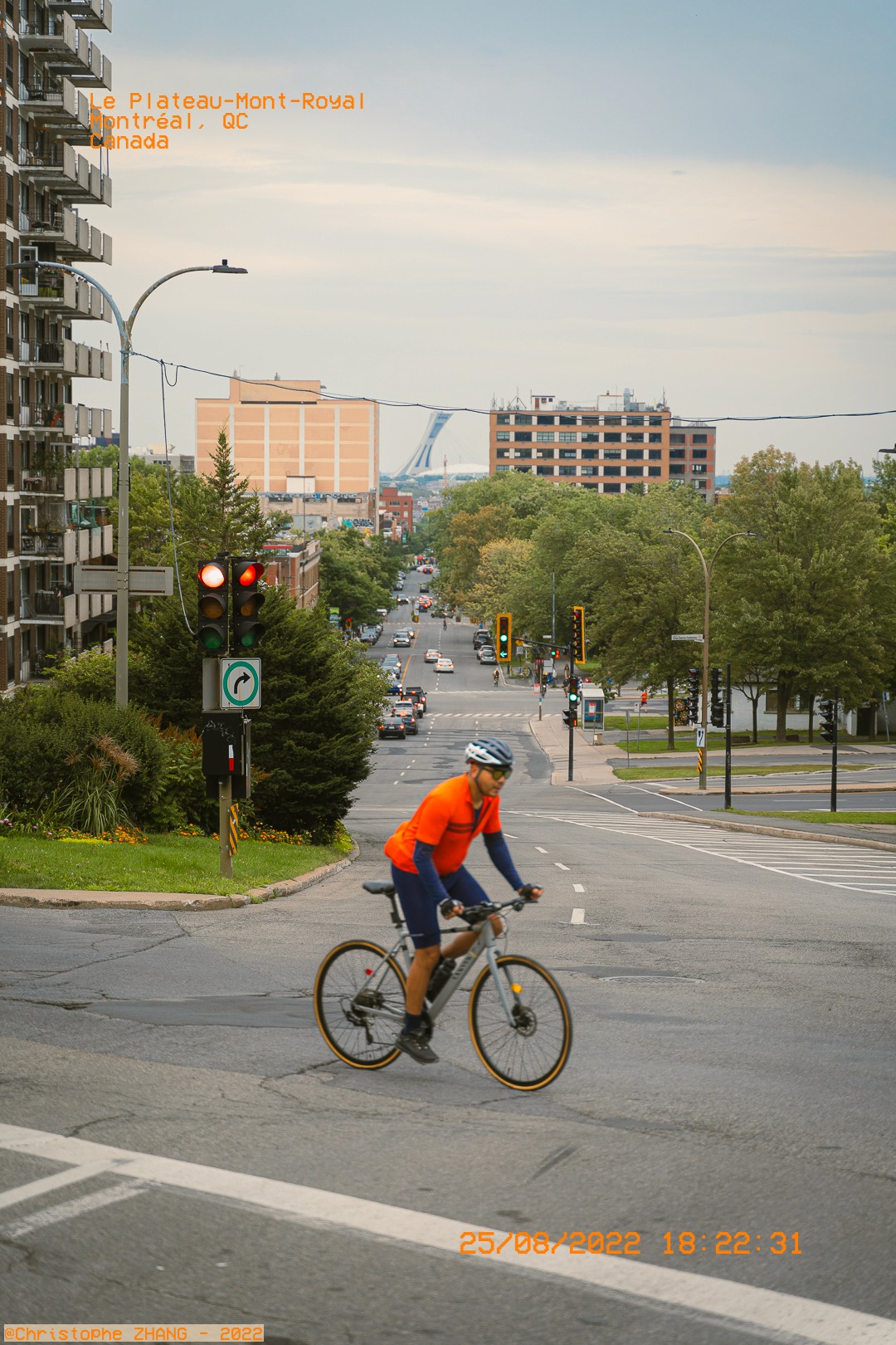 Scène urbaine dans le Plateau-Mont-Royal, avec un cycliste en premier plan et le Stade Olympique au loin.