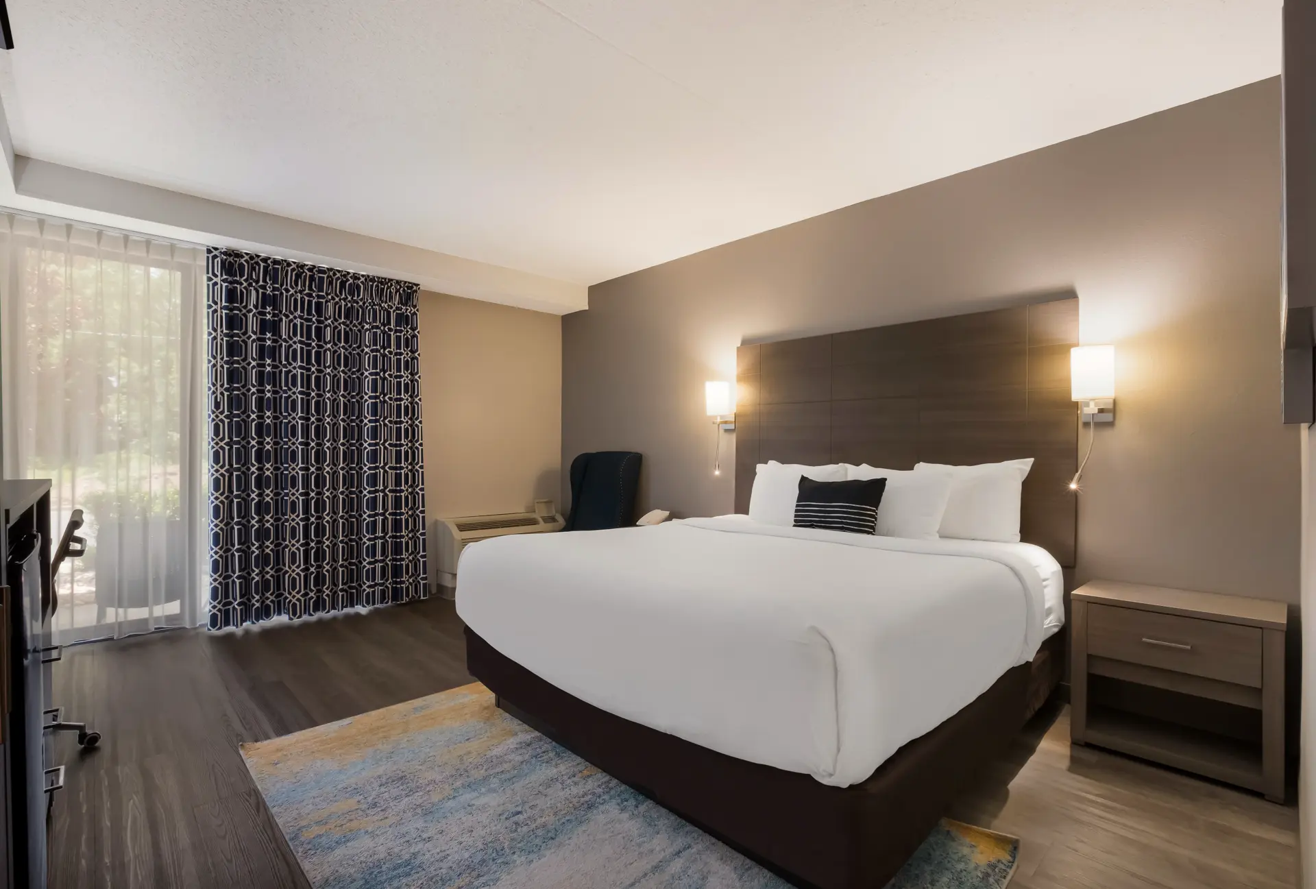 Hotel room with a bed, blue headboard, and gold marbled accent wall.
