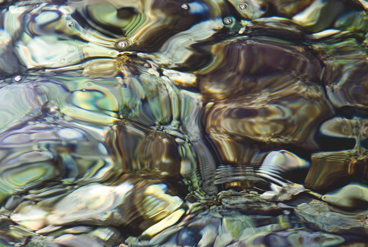 Gelbgrüne und violette Lichtreflexe bilden auf dem Wasser ein großes Wirbelmuster