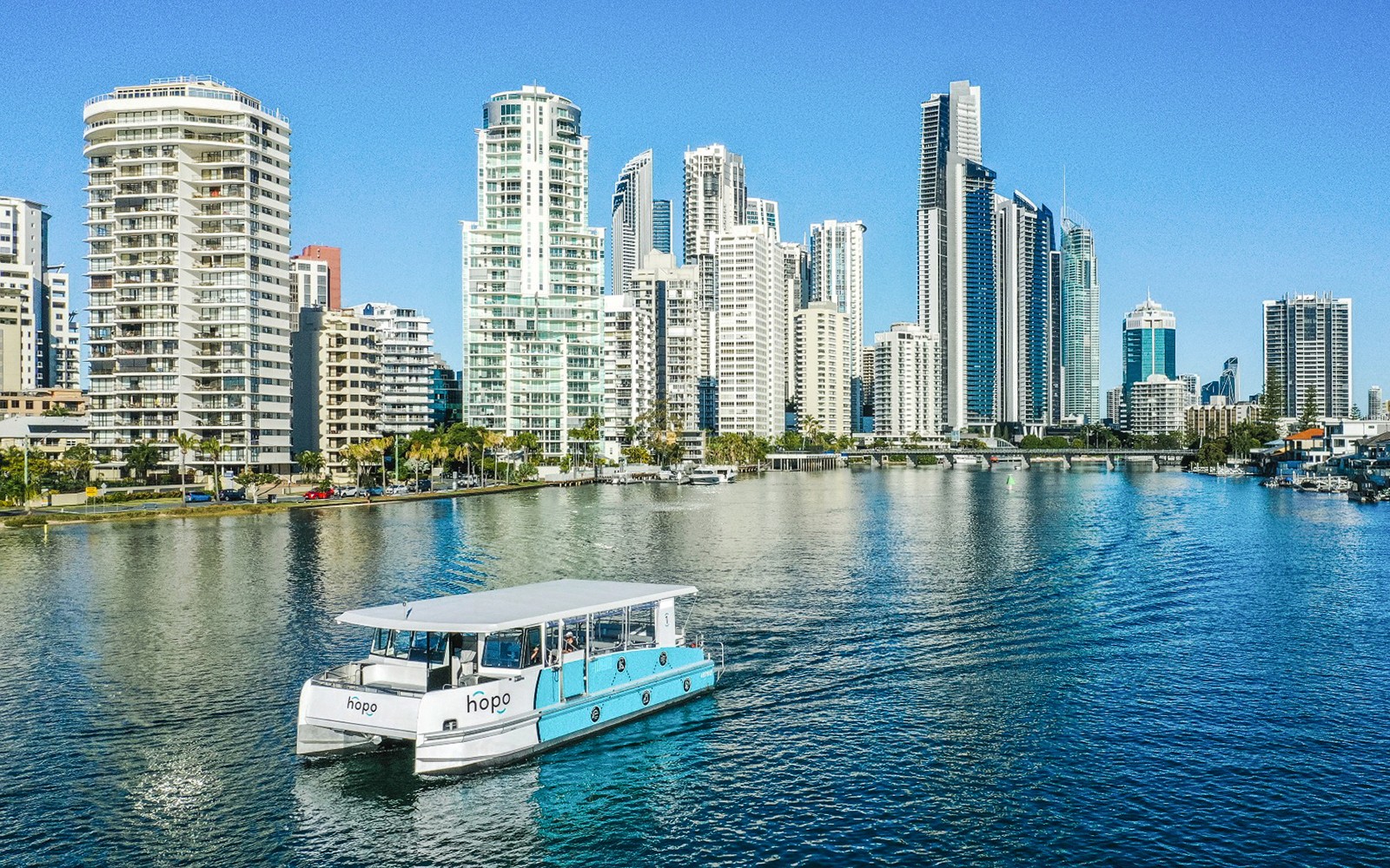 Hop On Hop Off cruise boat on Gold Coast waterway with city skyline in background.