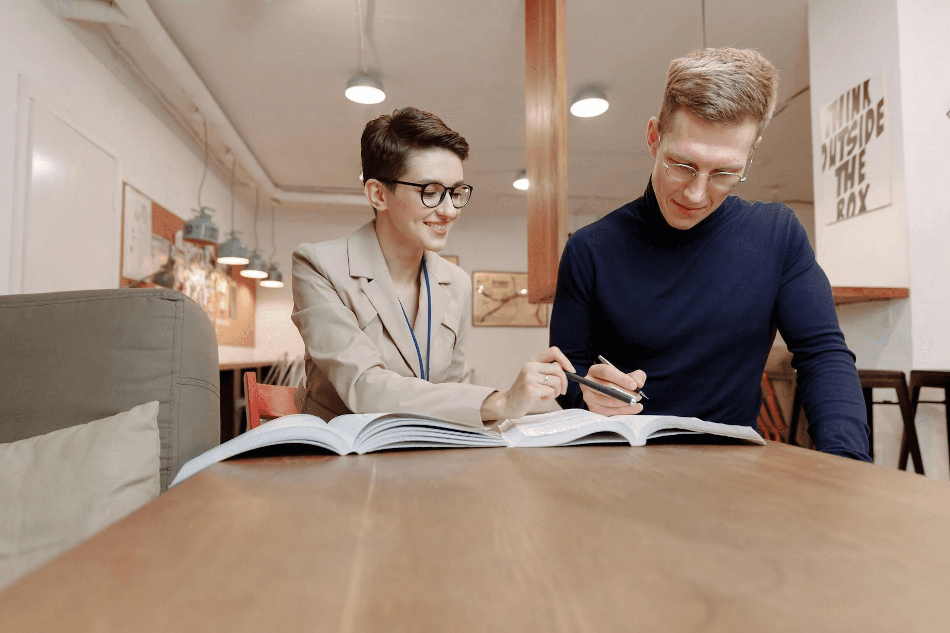 Two people looking at a book in an office.
