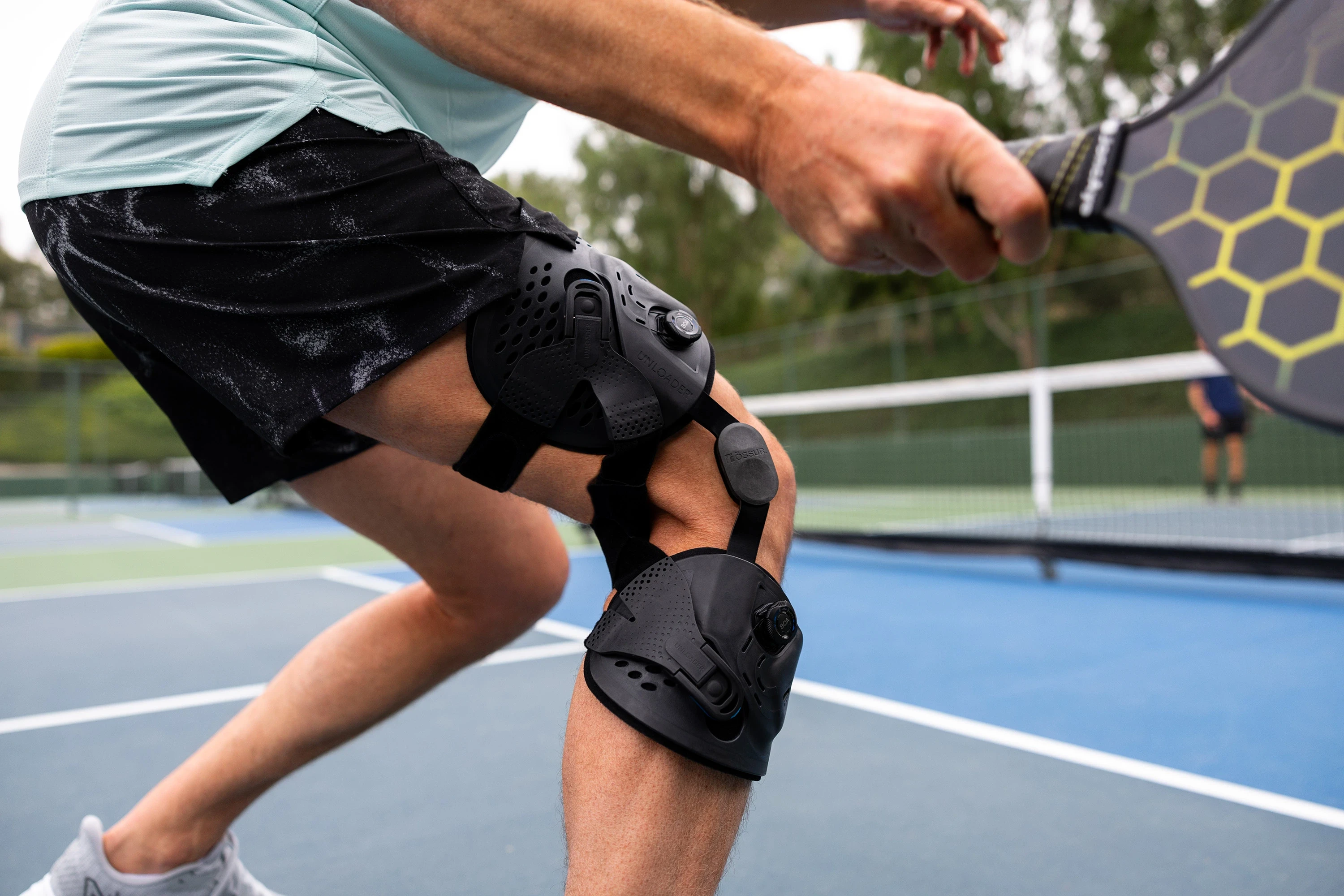 Alt text: Man playing tennis wearing an Unloader One knee brace, helping reduce knee arthritis pain and support mobility at Limitless Orthotics clinic, Leeds.