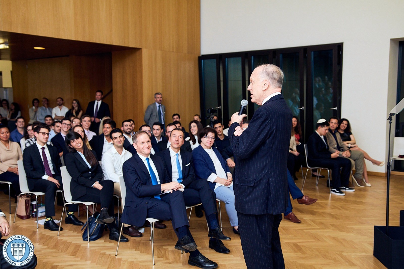 A lecture in a large LBS campus hall with students seated and listening to a presenter at the front