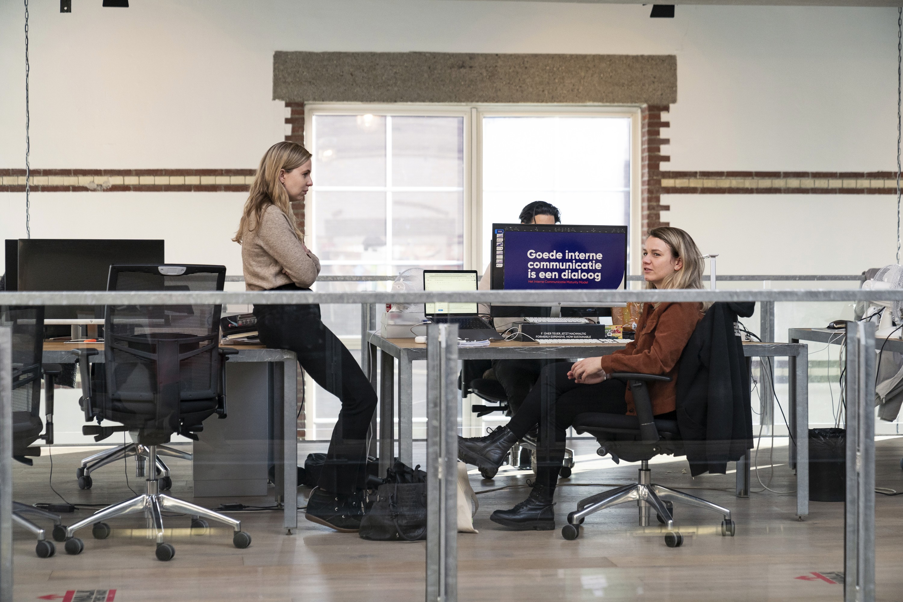 two women discussing work at their desks
