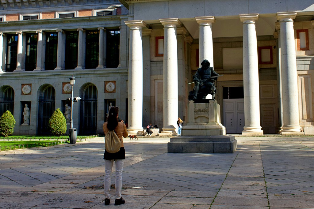 a woman taking a picture of a statue in front of a building
