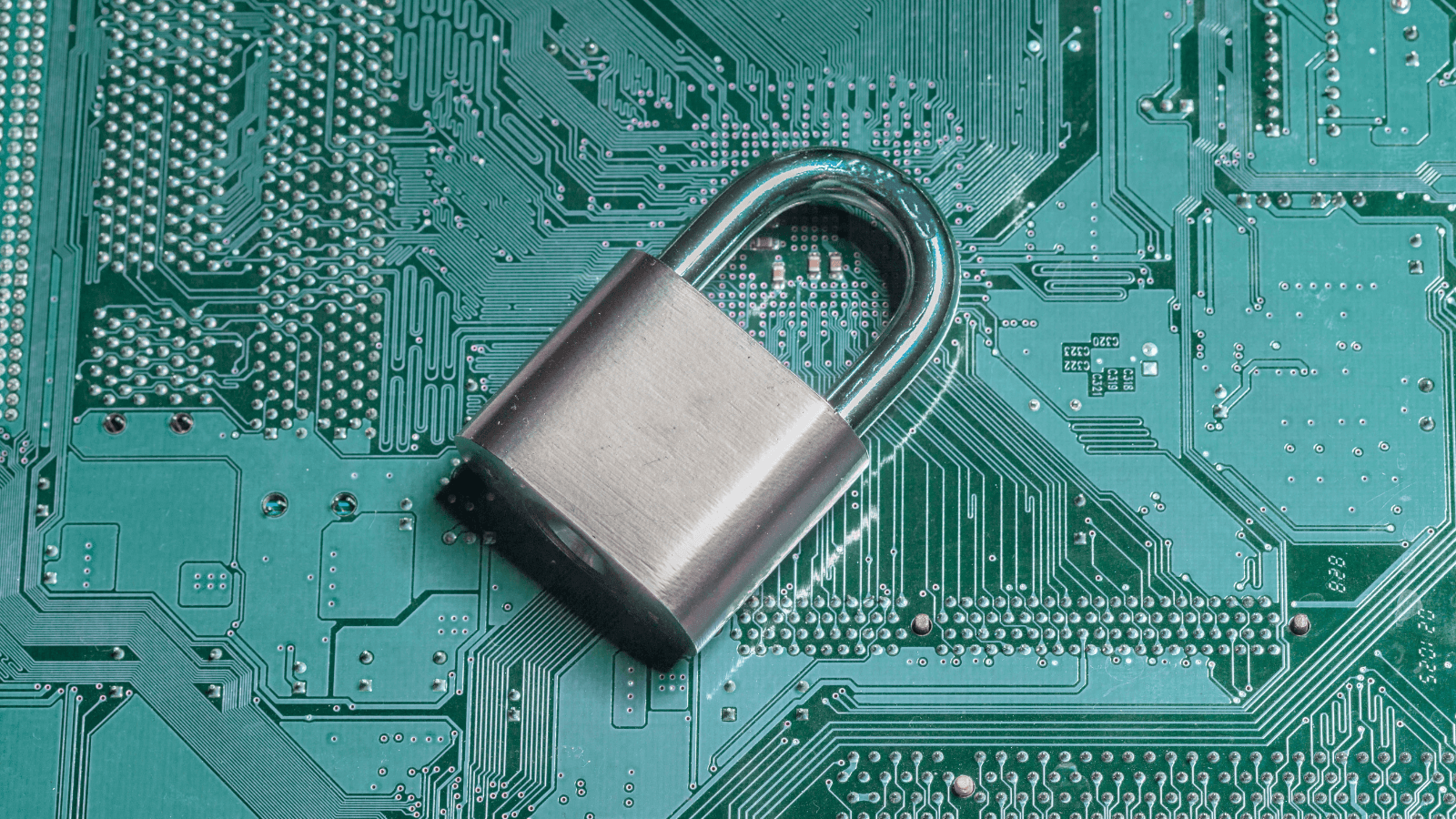 A silver padlock resting on a green circuit board background, symbolizing security and technology.