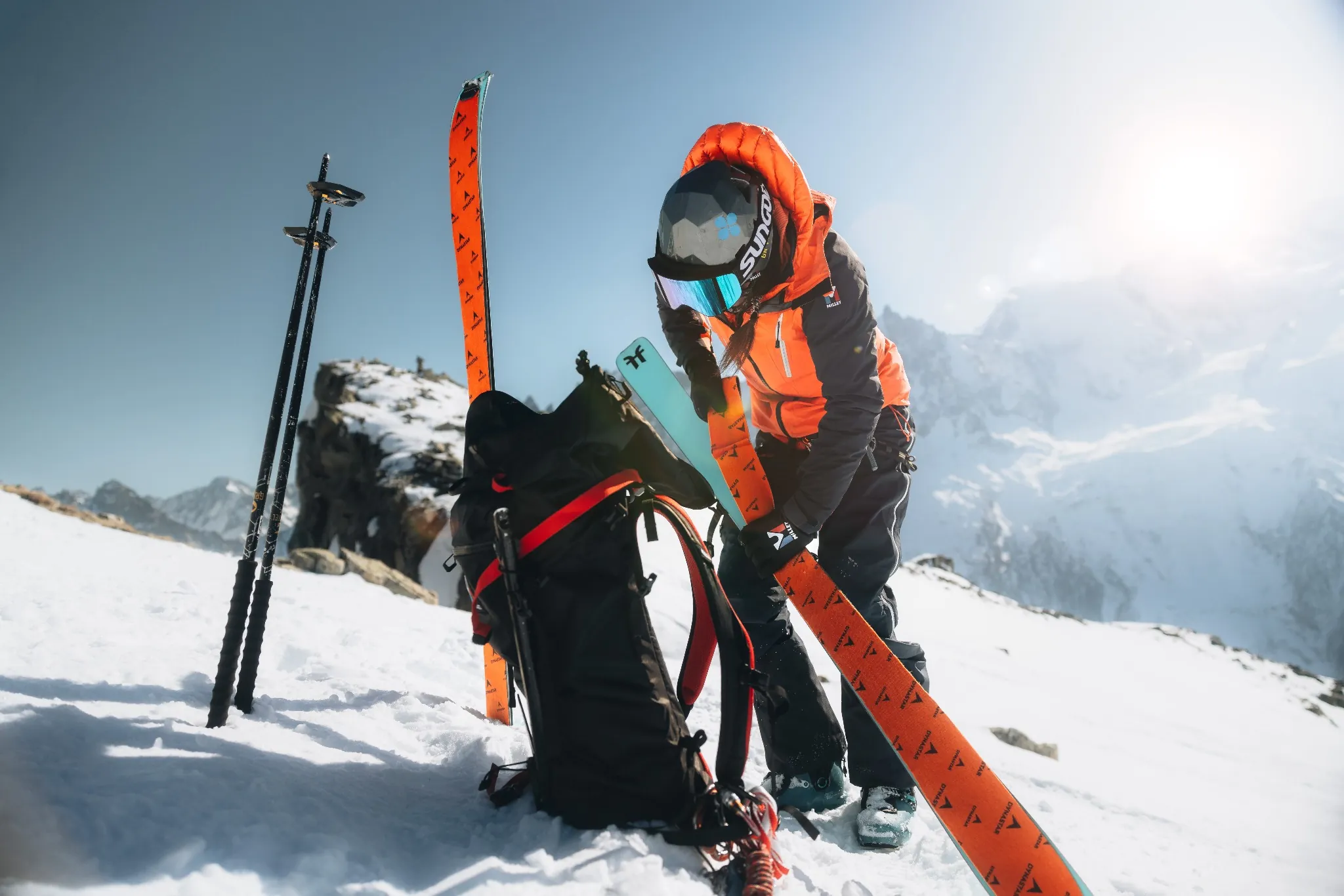 Skieuse Millet préparant son matériel sur un sommet enneigé.