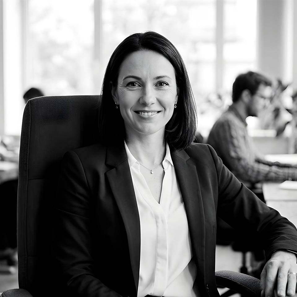 Portrait of a woman with straight long hair, in a dark t-shirt, set against a neutral backdrop.