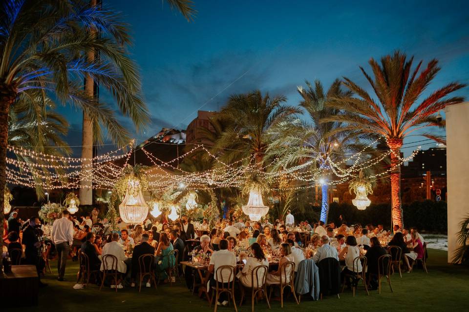 A beautifully set dining table with white tablecloth, cutlery, and fresh greenery in a cozy, well-lit space.