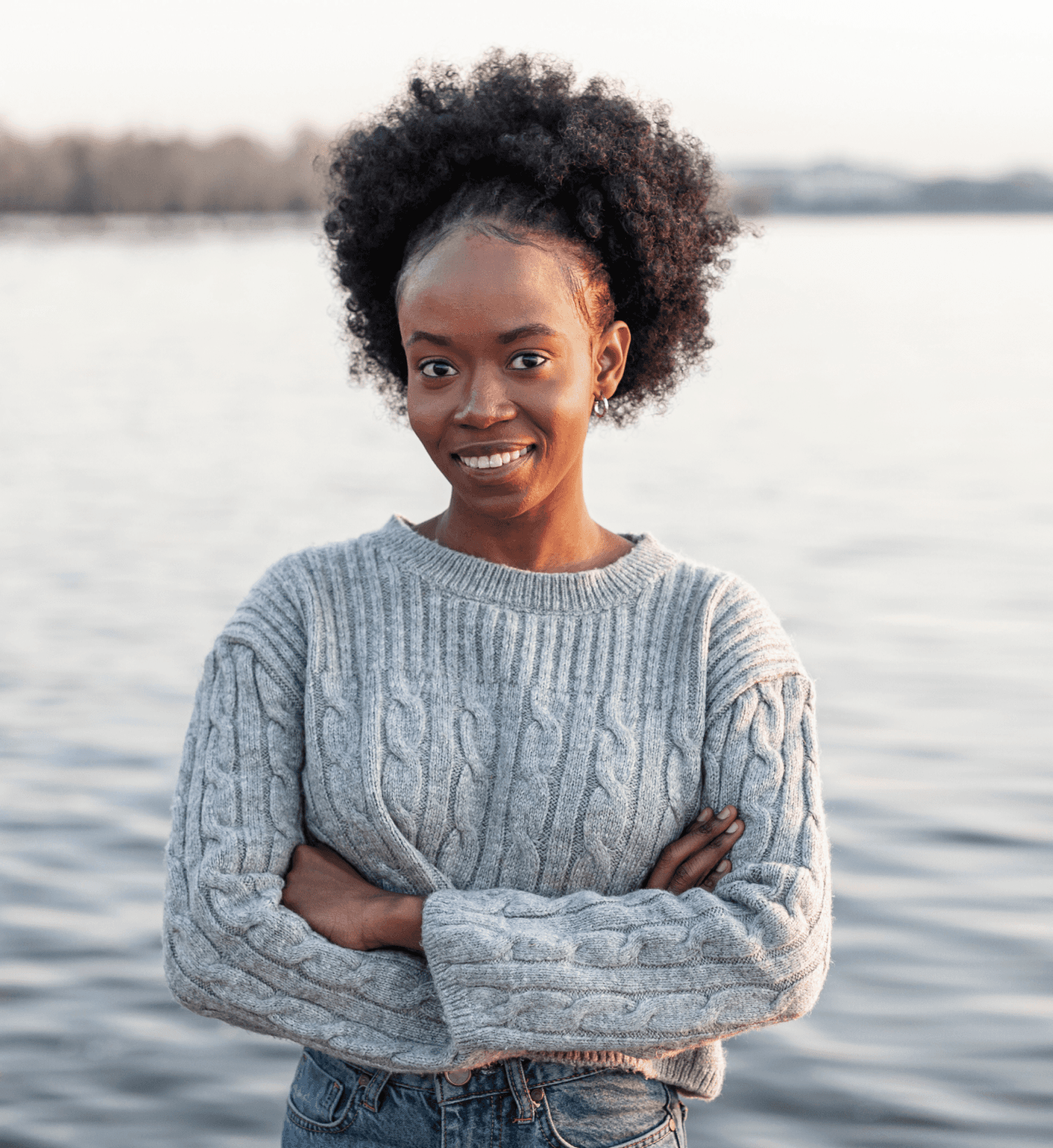 A woman in grey smiling with an ocean backdrop
