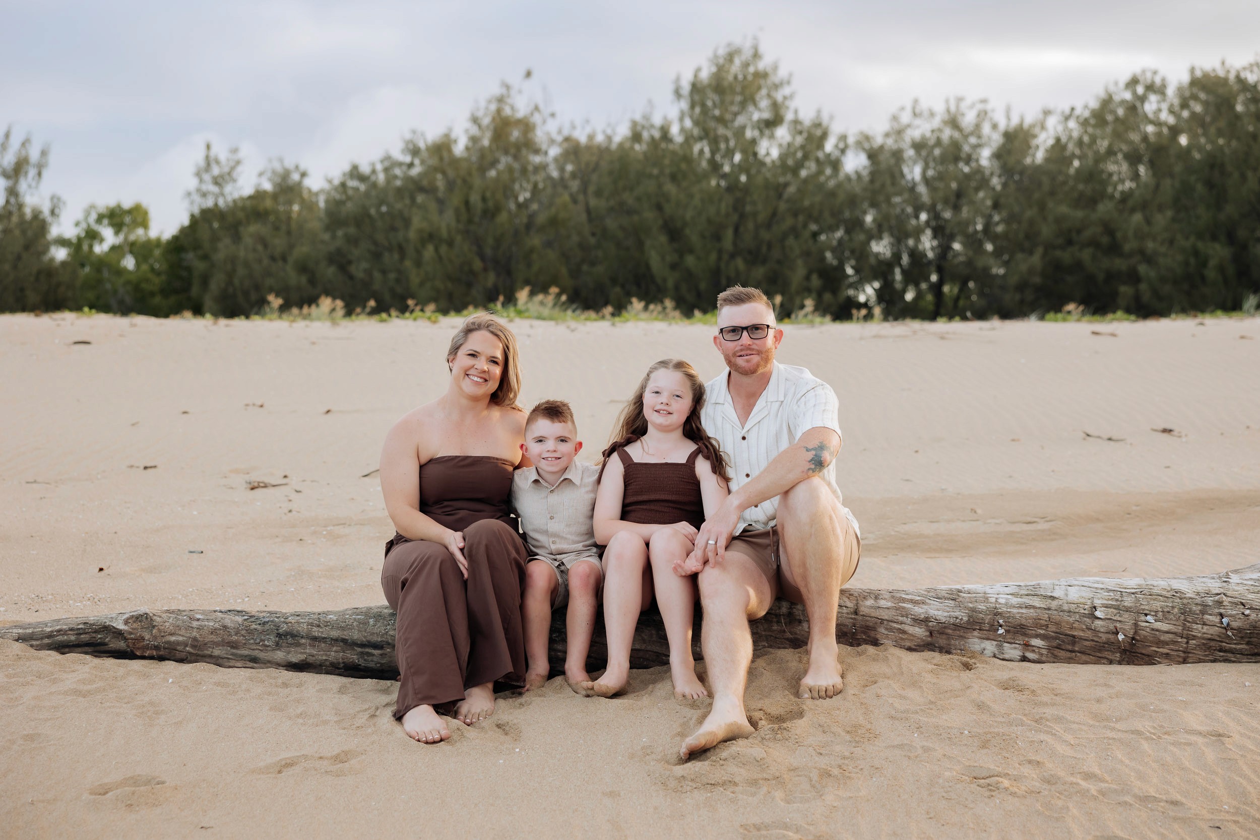 Family sitting on a log at the beach Mackay