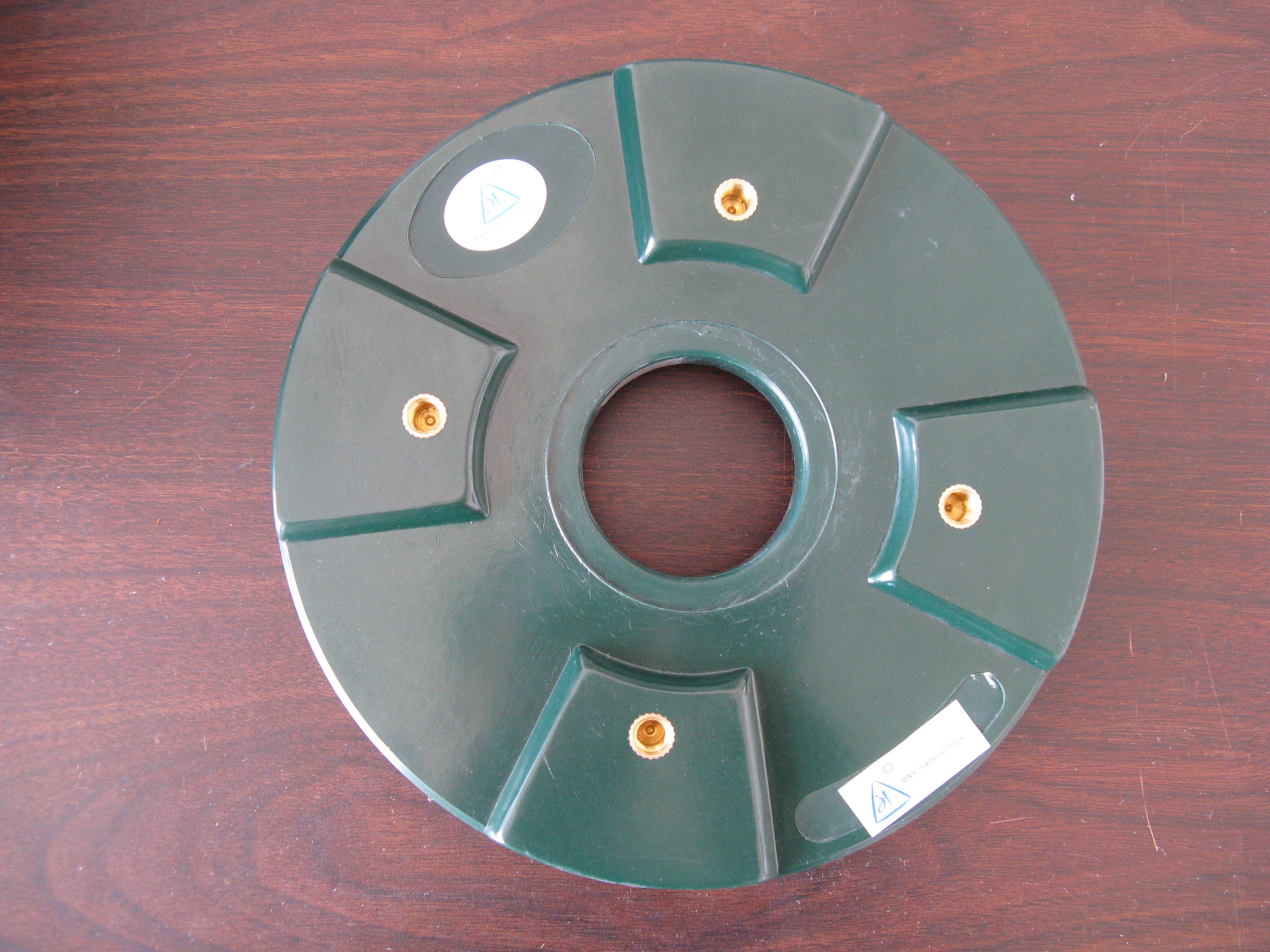 A green polishing disc with a dark green center, displayed on a wooden surface.