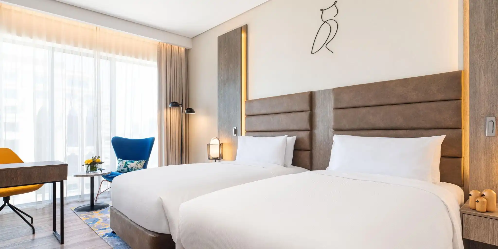 A guest room with floor-to-ceiling windows at voco Dubai The Palm, a pet-friendly hotel on Palm West Beach