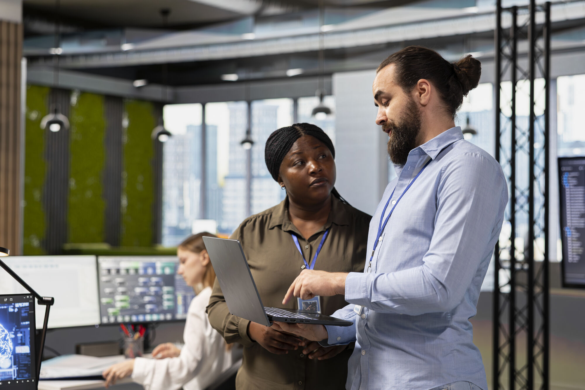 A man in a white lab coat working at a computer, viewing a 3D model on the screen in a laboratory or office setting.