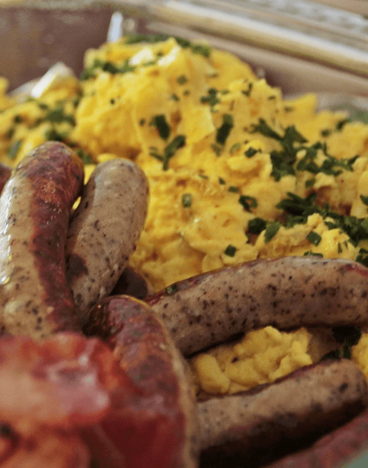 Flammkuchen auf einem Tisch mit zwei Biergläsern; eine Hand greift nach einem Glas.