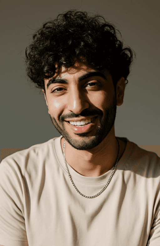 A man with curly hair smiles warmly, showcasing a friendly and approachable demeanor.