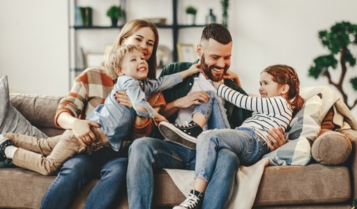 Family sitting on a couch at home smiling and playing games together.