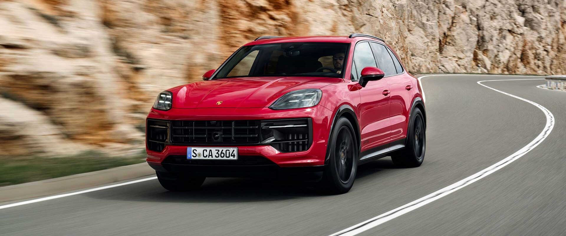 Red luxury SUV driving on a mountain road