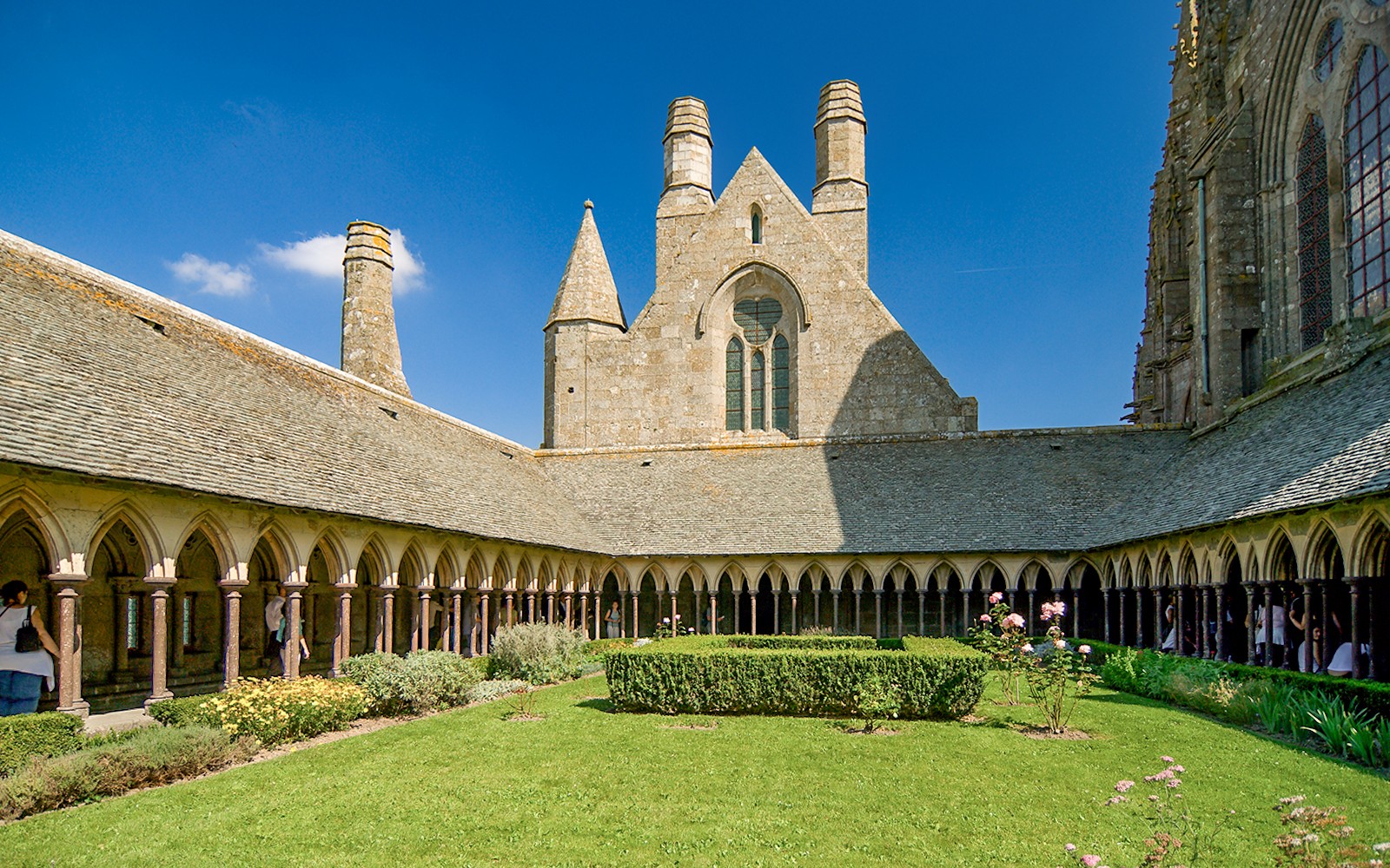 Mont St. Michel Abbey cloister with tourists on a full-day tour from Paris.