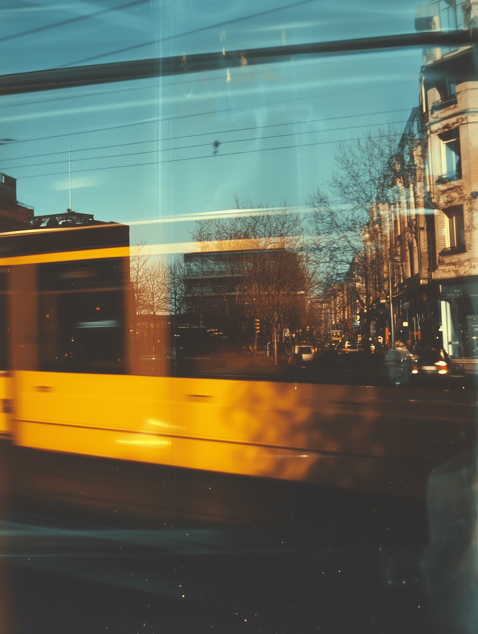 Photograph of a yellow bus window, Kodak film photograph., a blurred urban street on a sunny day, golden tone, in front of the camera