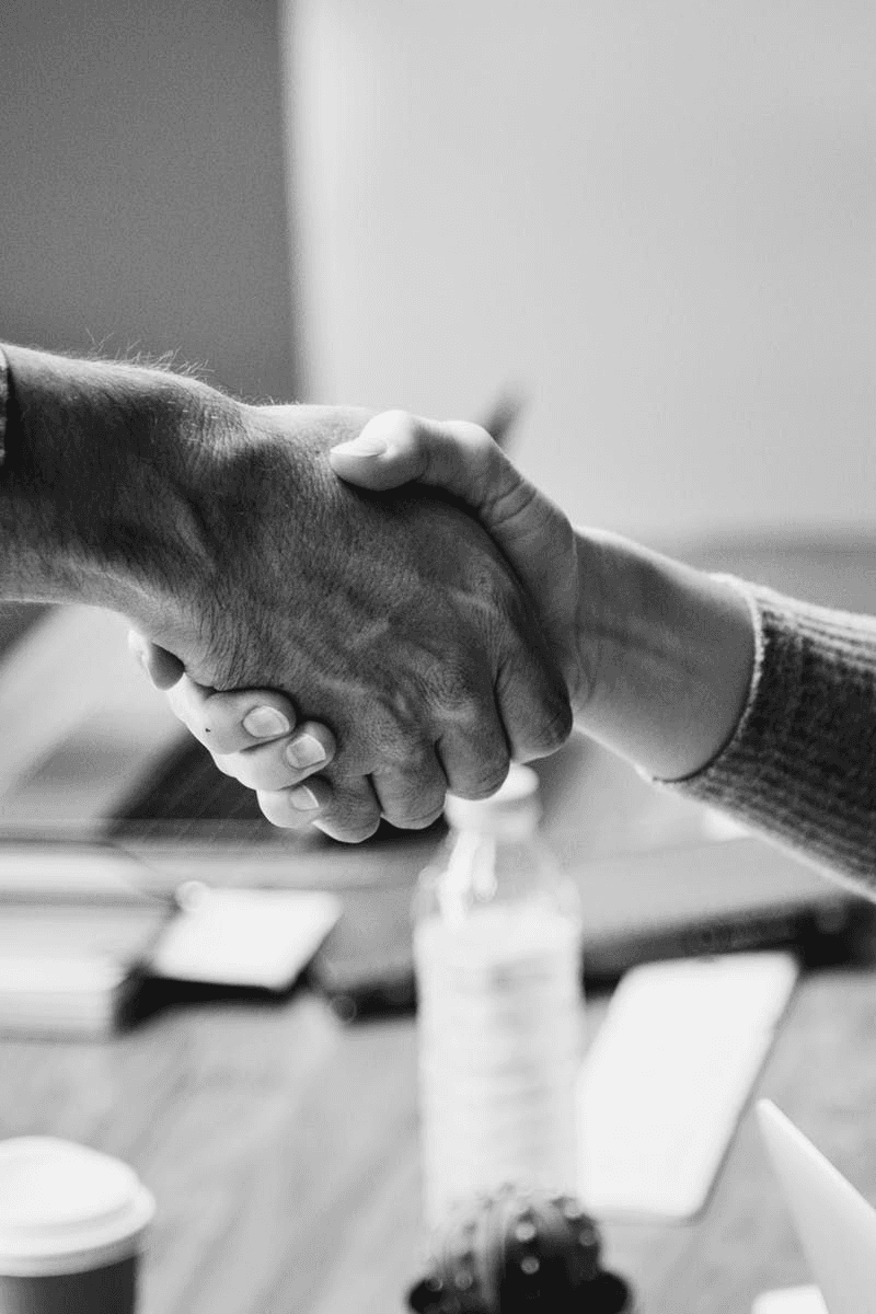 two men facing each other while shake hands and smiling