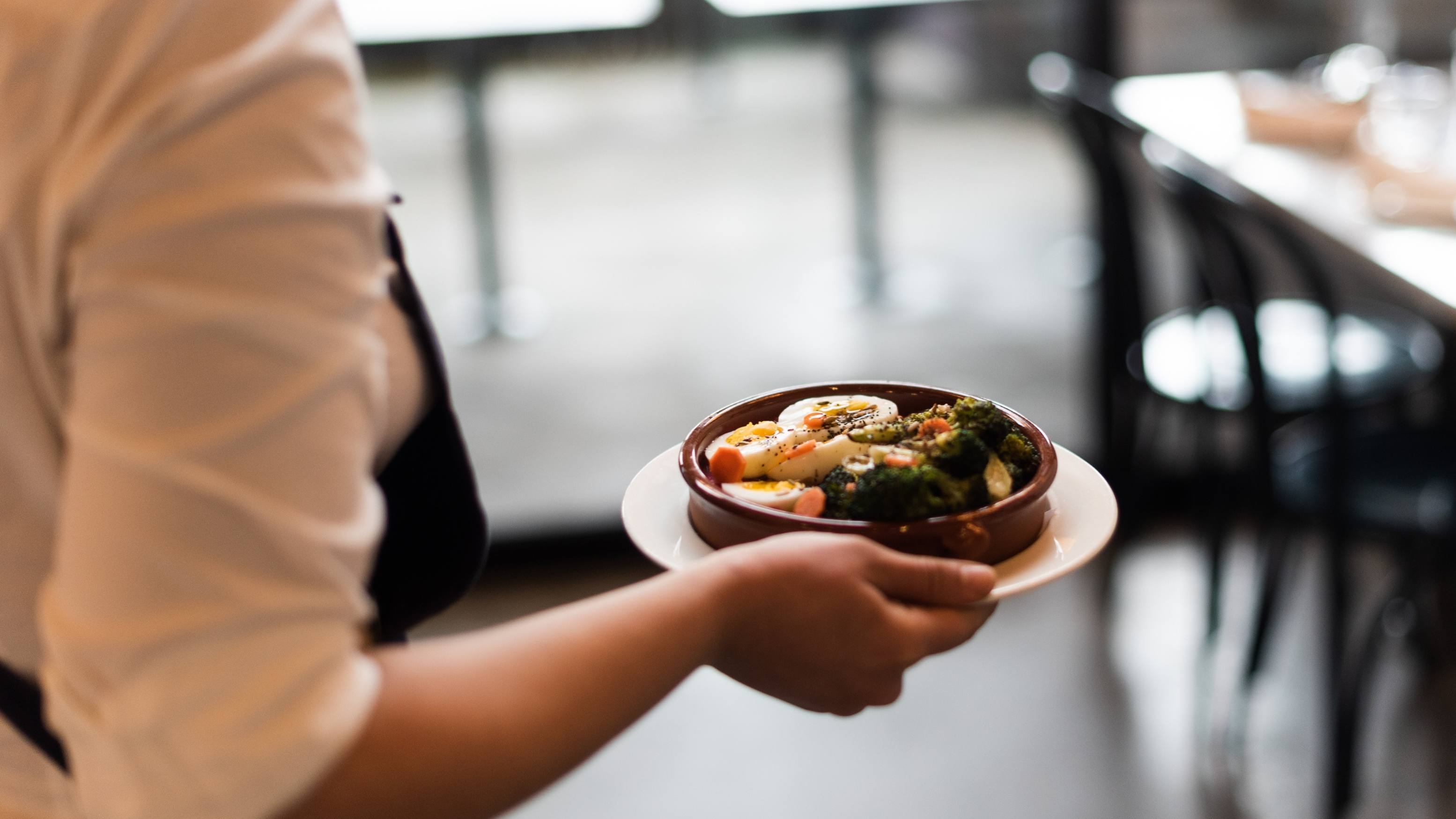 一位马来西亚餐厅员工正为顾客送上一盘菜