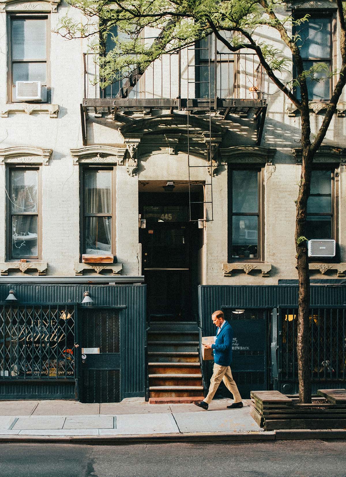A man walking on a New York City street in front of an apartment building
