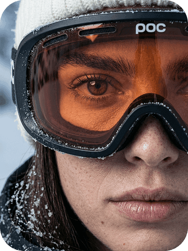 Extreme close-up portrait of a woman wearing ski goggles, snowy outdoor environment