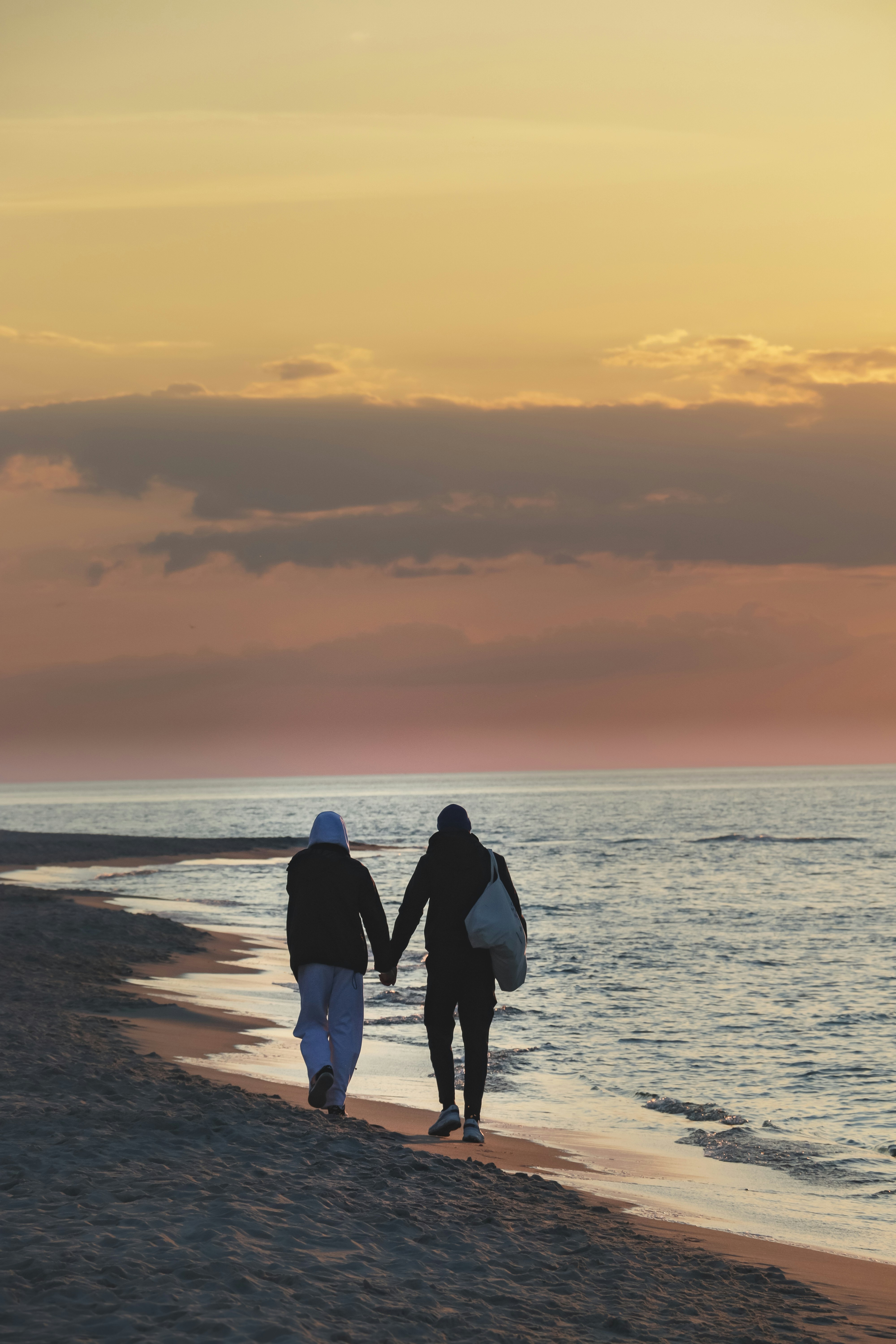 two people walking on a beach holding hands