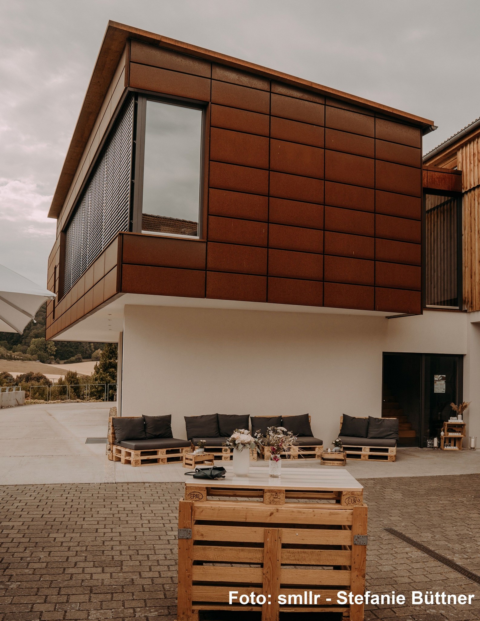 Moderne Architektur des Weinguts Neder in Ramsthal mit gemütlichen Paletten-Loungemöbeln im Außenbereich.