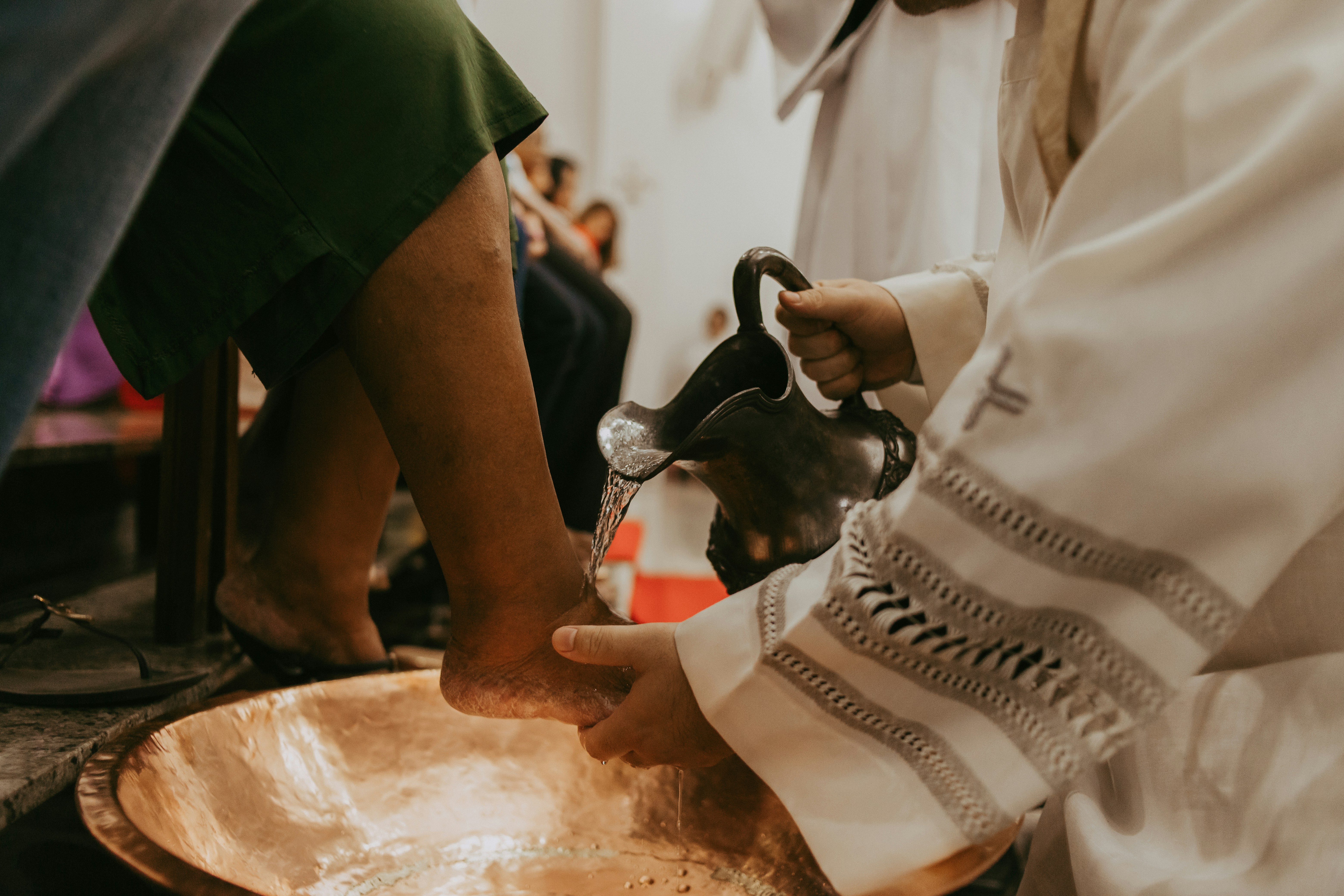 a close up of a person pouring water into a bowl while someone is washing another persons feet