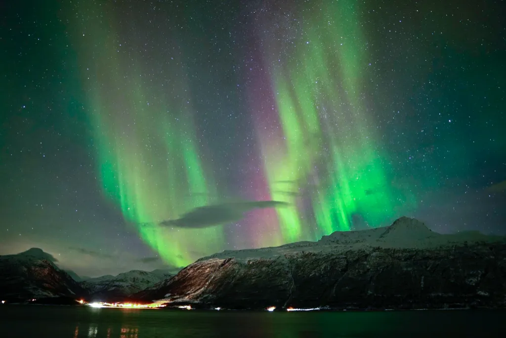snow covered mountains near body of water during night time