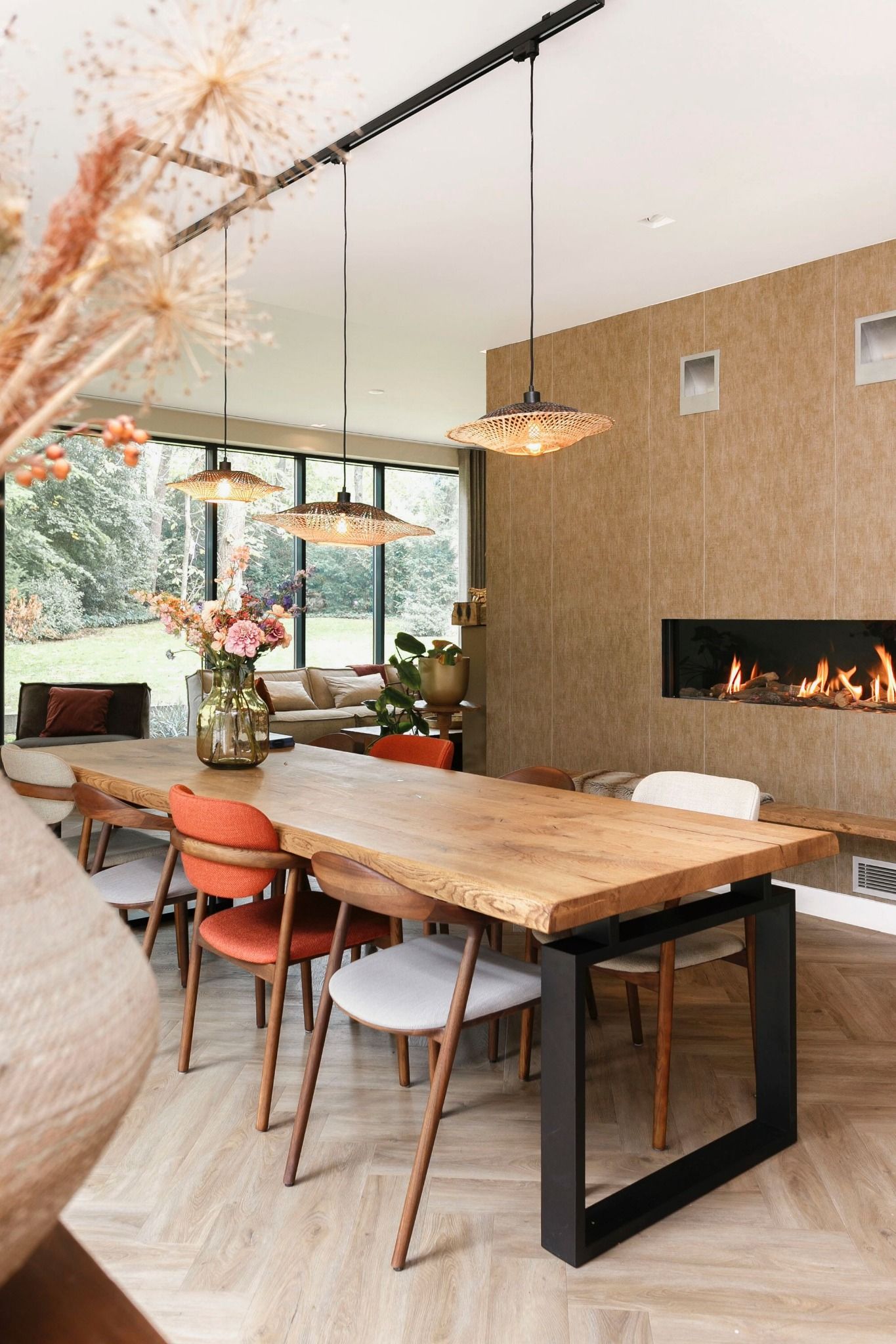 eettafel verschillende stoelen en gashaard met rotan hanglampen