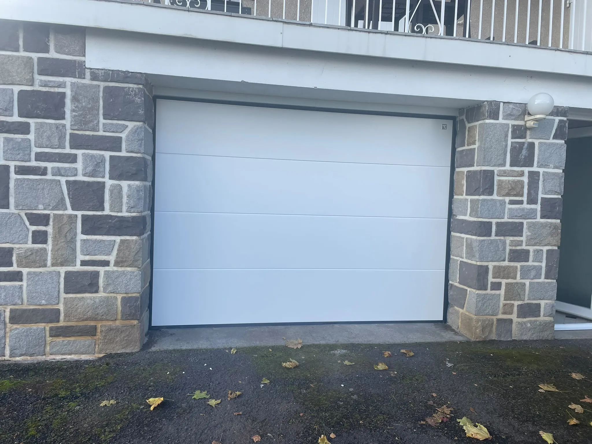 Porte de garage blanche entourée de parements — AFermetures