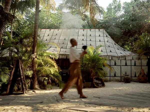 Person walking in front of a cabin located in the jungle at Nômade Tulum, Mexico.