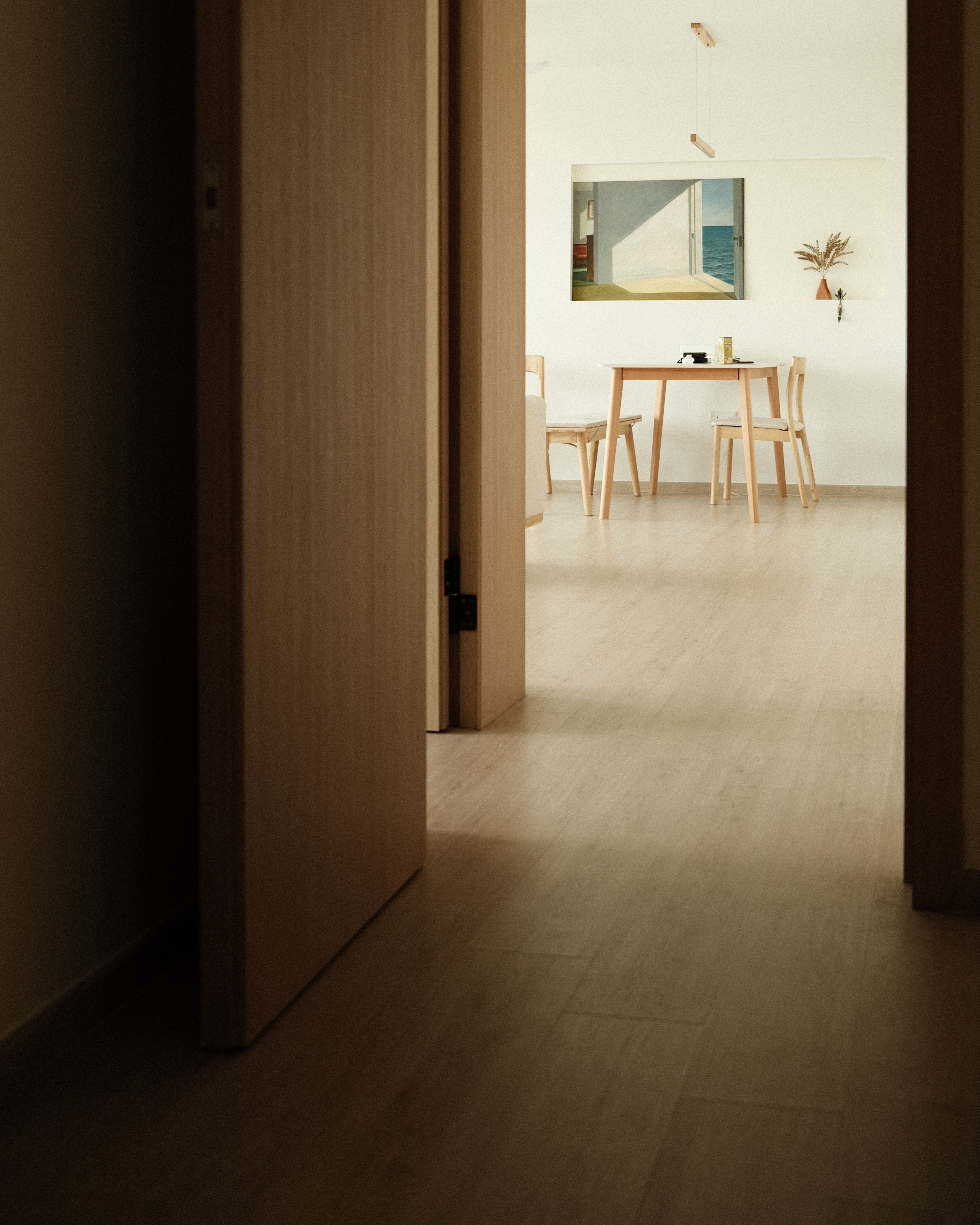 Hallway view towards dining area with natural light and wood flooring, open concept HDB design Singapore