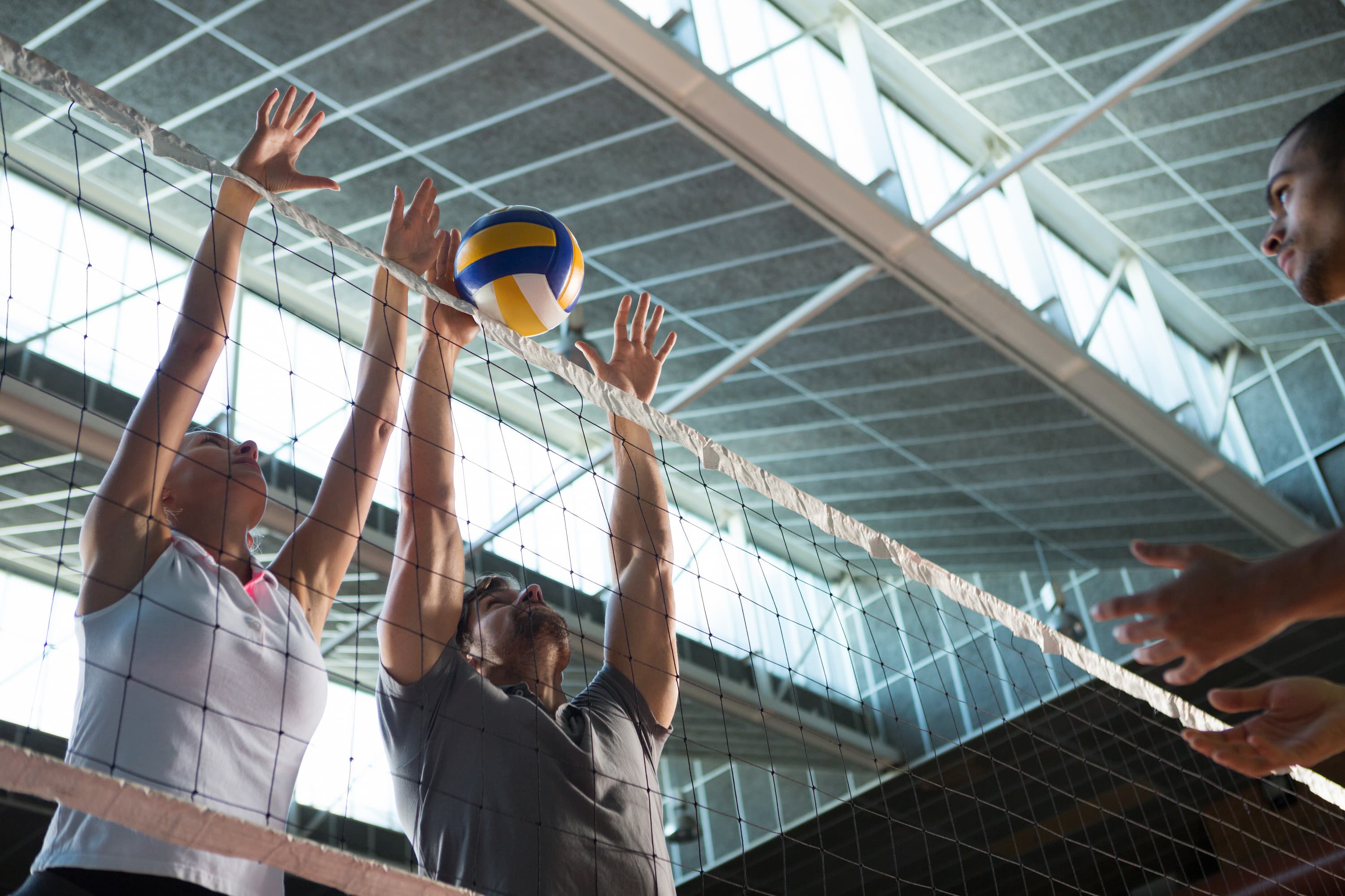 Two volleyball players blocking a spike during a Pianeta Sport Volleyball Tour match