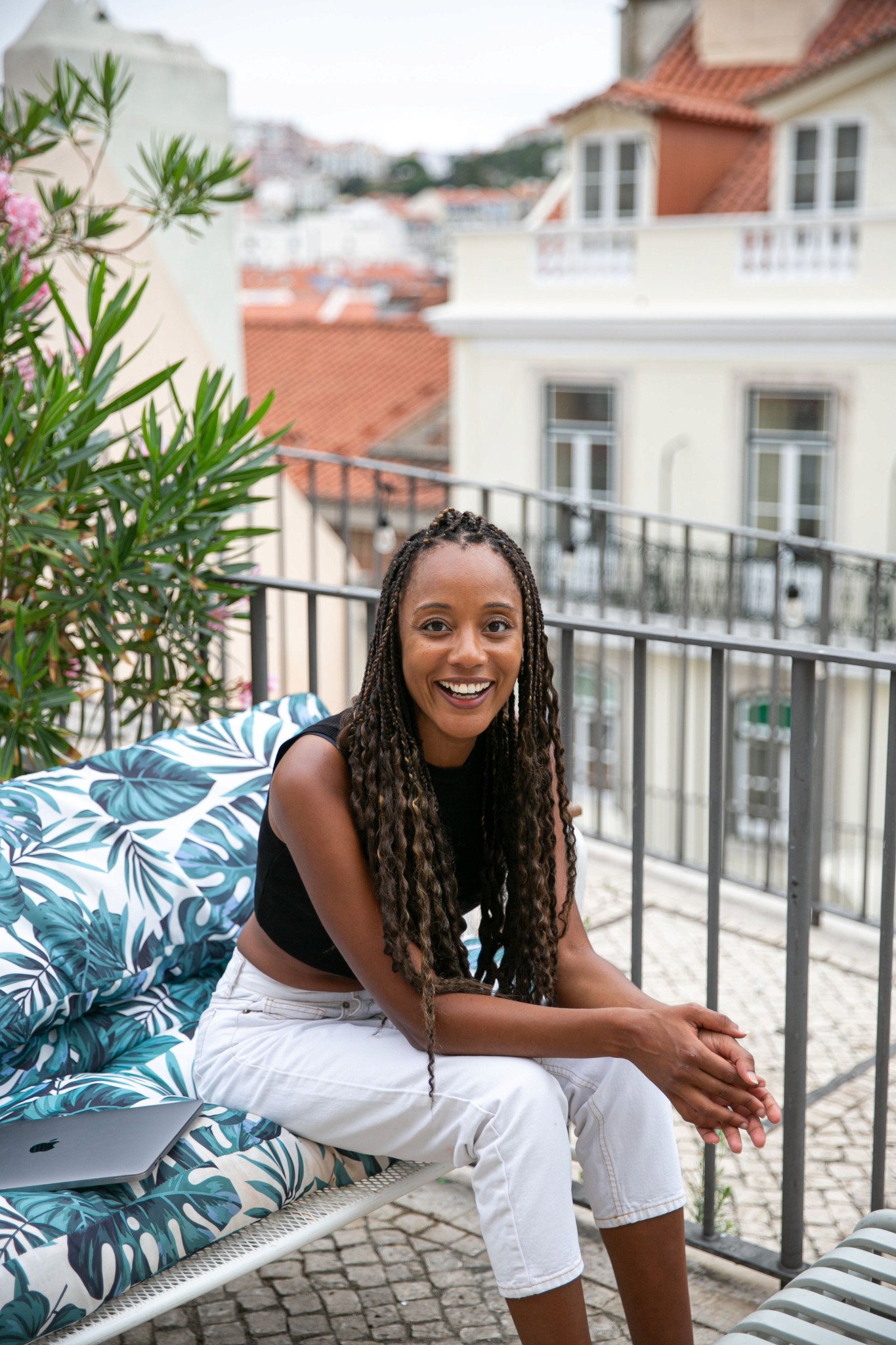 Rita Batalha smiling while sitting on a couch outdoors